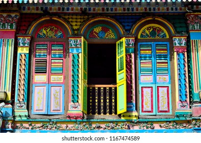 Colorful exterior of historic Singapore shophouse with arched windows and antique wooden shutters in historic Little India
