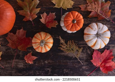 Colorful Fall Leaves And Pumpkins On A Rustic Wood Table