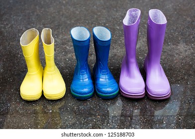 Colorful Family Boots At Rainy Day On Street