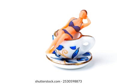 Colorful female figurine in bikini relaxing atop a decorative tea cup, representing stress relief and leisure. - Powered by Shutterstock