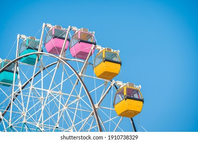 Colorful ferris wheel in an amusement park against blue sky