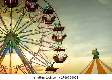 Colorful ferris wheel at sunset, illuminated by neon lights with a circus tent. Background with copy space. Rosolina Mare amusement park, Veneto, Italy.