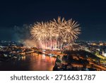 Colorful fireworks exploding above Chao Phraya River with Memorial Bridge and illuminated bangkok cityscape in Thailand