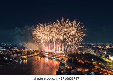 Colorful fireworks exploding above Chao Phraya River with Memorial Bridge and illuminated bangkok cityscape in Thailand