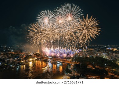 Colorful fireworks exploding above Chao Phraya River with Memorial Bridge and illuminated bangkok cityscape in Thailand