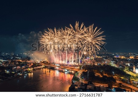 Colorful fireworks exploding above Chao Phraya River with Memorial Bridge and illuminated bangkok cityscape in Thailand