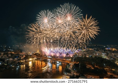 Colorful fireworks exploding above Chao Phraya River with Memorial Bridge and illuminated bangkok cityscape in Thailand