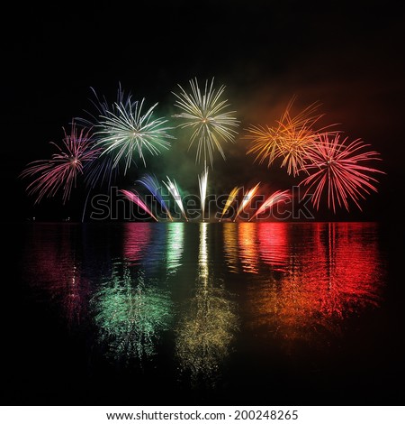 Colorful fireworks with reflection on lake and night sky in background.