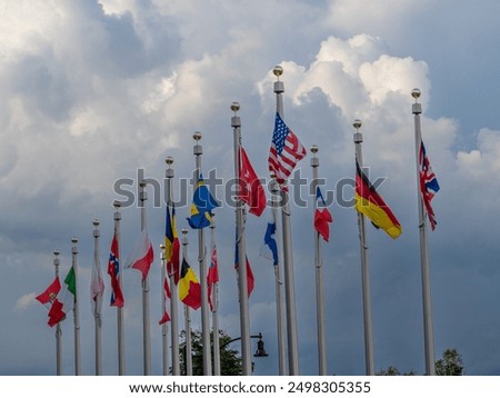 Colorful flags from around the world flutter majestically in the breeze against a cloudy sky outside the iconic Olympic Center in downtown Lake Placid, Upstate New York.