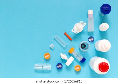 Colorful flat lay of vision correction lenses equipment on blue background with copy space : eye drops, containers, lenses, twizzlers, liquids