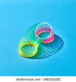 Colorful flexible spring with shadows on a pastel blue background with copy space.