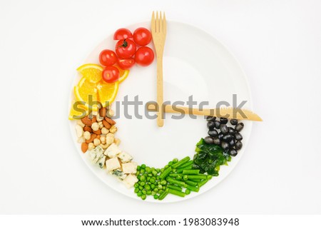 Colorful food and cutlery arranged in the form of a clock on a plate. Intermittent fasting, diet, weight loss, lunch time concept.