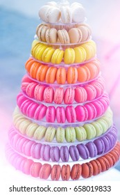 Colorful french macarons, multilevel cake pyramid, on plastic, dessert stand or plate on blurred background. Food, dieting. Birthday, anniversary, wedding celebration