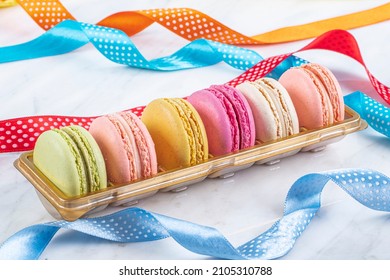 Colorful french macarons on marble floor. Macaron or Macaroon sweet meringue-based confection. Stack of fresh colorful macarons. 