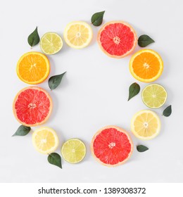 Colorful Fruit Circle Frame Of Fresh Citrus Slices With Leaves. Top View, Flay Lay Over A White Background With Copy Space.