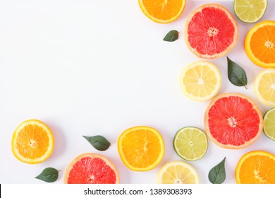 Colorful Fruit Corner Border Of Fresh Citrus Slices With Leaves. Top View, Flay Lay Over A White Background With Copy Space.