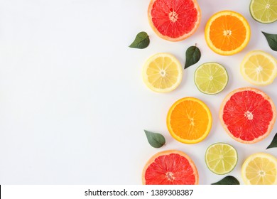 Colorful Fruit Frame Of Fresh Citrus Slices With Leaves. Top View, Flay Lay Over A White Background With Copy Space.