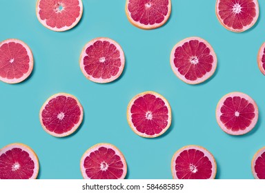 Colorful Fruit Pattern Of Fresh Grapefruit Slices On Blue Background. From Top View