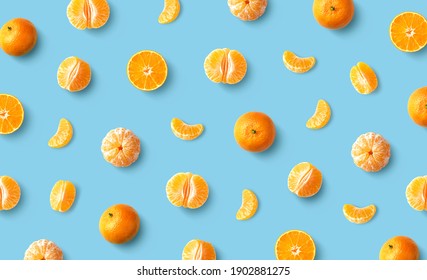 Colorful fruit pattern of fresh mandarin tangerine or clementine on blue background, flat lay, top view