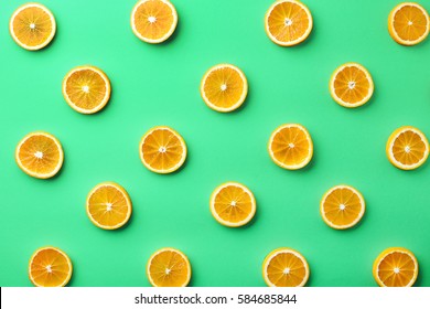 Colorful fruit pattern of fresh orange slices on green background. From top view - Shutterstock ID 584685844