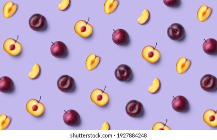 Patrón de fruta colorido de ciruela fresca entera y cortada sobre fondo morado, puesta plana, vista superior Foto de stock