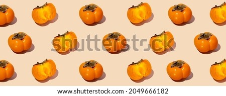 Colorful fruit pattern of fresh whole and sliced organic persimmon fruit with leaves on beige-pink background. Healthy eating and food concept. Flat lay, top view. Design element