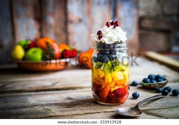 Colorful\
fruit salad in a jar on rustic wooden\
background