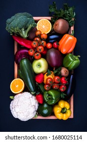 Colorful fruits and vegetables in a wooden box on a dark background. A set of products for healthy eating. Concept of eco food, detoxification of the body and weight loss. 