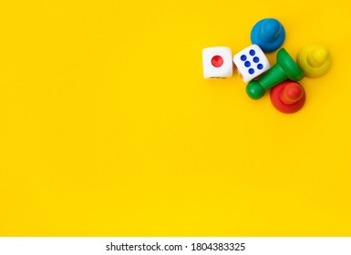 Colorful game chips and two dice are laid out on a yellow background: entertainment, games at home for the whole family, the concept of Board games. Board game. Table games, space for text - Shutterstock ID 1804383325