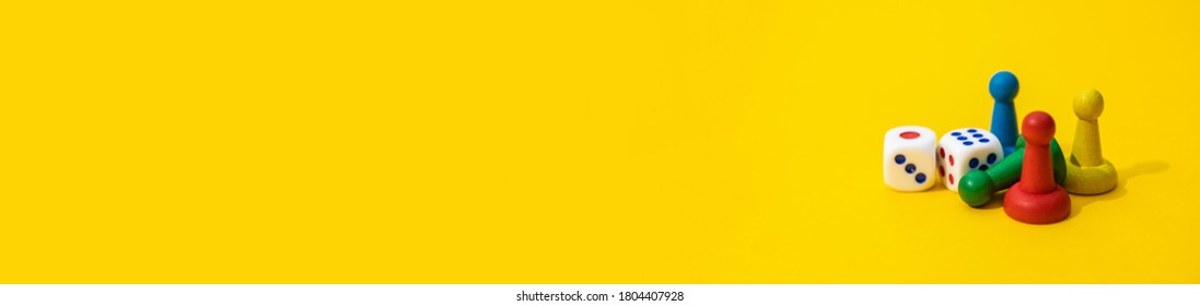 Colorful game chips and two dice are laid out on a yellow background: entertainment, games at home for the whole family, the concept of Board games. Board game. Selective focus, banner, space for text - Shutterstock ID 1804407928