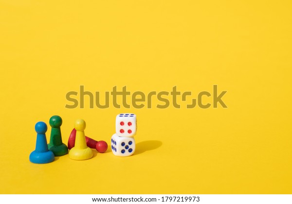 黄色い背景にカラフルなゲームチップと2つのサイコロが配置される 娯楽 家族全員の家庭でのゲーム ボードゲームのコンセプト ボードゲーム 卓上ゲーム の写真素材 今すぐ編集