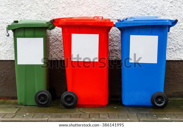 Colorful garbage\
trash cans aligned near the\
wall