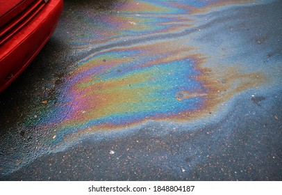 Colorful Gas Stain On Wet Asphalt. Oil Stain Caused By A Leak Under A Car.Environmental Pollution Concept.