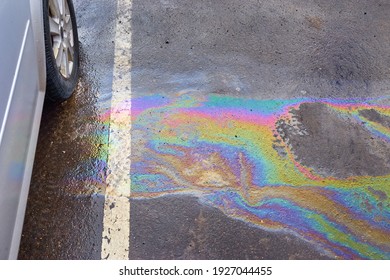 Colorful Gas Stain On Wet Asphalt. Oil Stain Or Gasoline Caused By A Leak Under A Car. Environmental Pollution Concept.