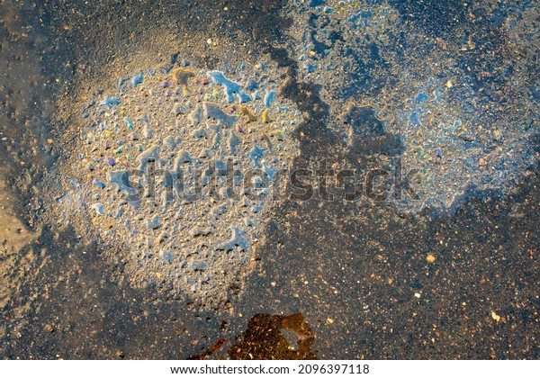 Colorful gas stain\
on wet asphalt. Oil stain caused by a leak under a car or truck.\
Environmental pollution\
concept