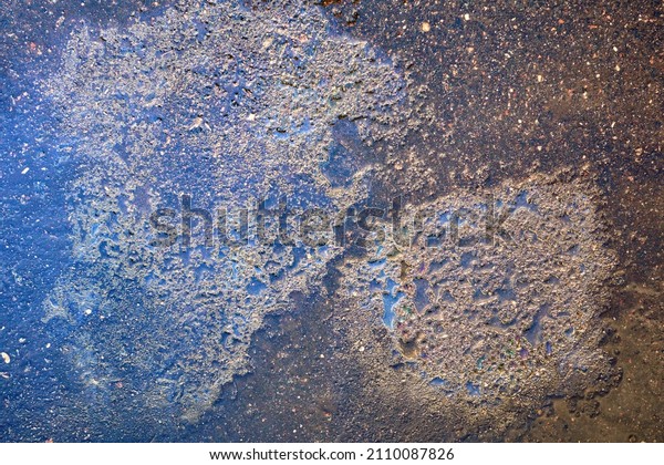 Colorful gas stain\
on wet asphalt. Oil stain caused by a leak under a car or truck.\
Environmental pollution\
concept