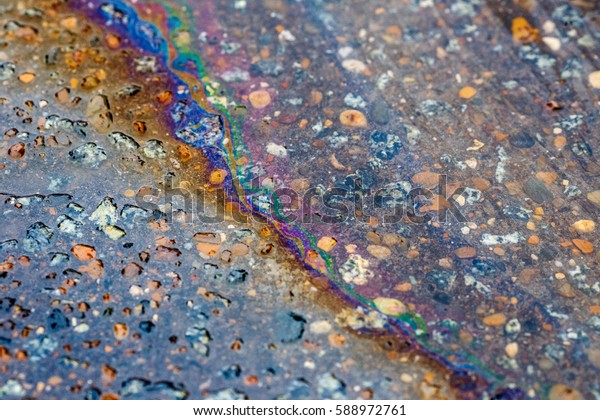 Colorful gas stain on wet\
asphalt. This is the type of stain caused by a leak under a car or\
truck.\
