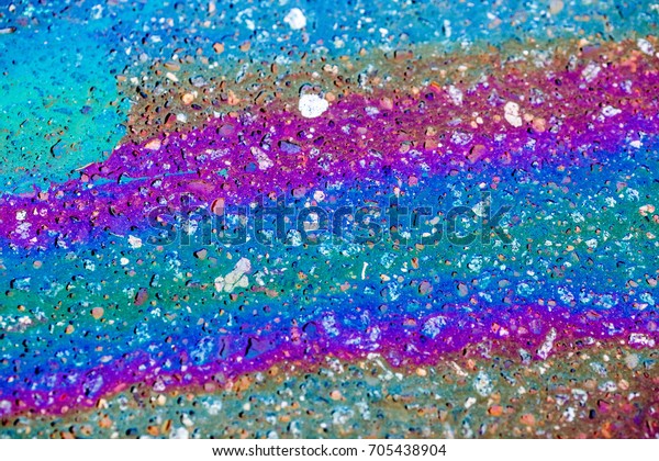Colorful gas stain on wet\
asphalt. This is the type of stain caused by a leak under a car or\
truck.\
