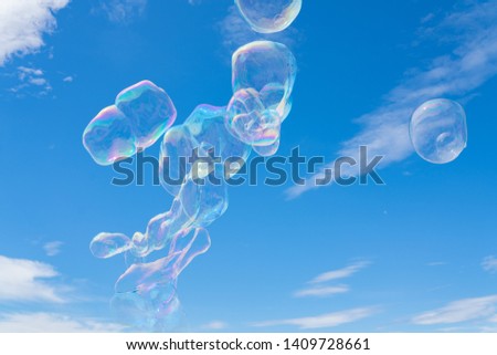 Colorful giant soap bubbles floating in the sky against the blue sky with scattered clouds.