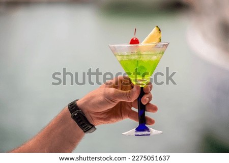 colorful gin tonic cocktails in glasses on on hand in yacht and sea background. hand cheers glass of cocktails cool drinks or Mocktail blended fruit margaritas, passionfruit drinks.