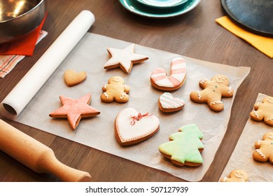 Colorful gingerbread cookies on culinary parchment. Kitchen table with traditional Christmas food. Cooking, winter, holiday, food, sweet concept - Powered by Shutterstock