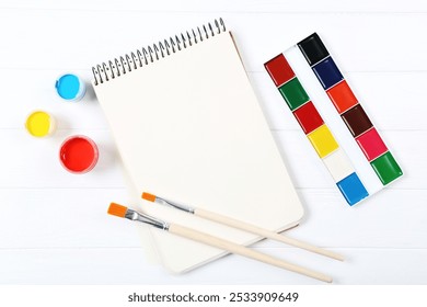 Colorful gouache paints with brushes and blank sheet of paper on white wooden table - Powered by Shutterstock