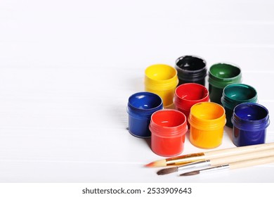 Colorful gouache paints and brushes on white wooden table - Powered by Shutterstock