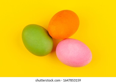 Colorful handmade Easter eggs. Top view of three eggs. Isolated on a yellow background. Preparing for Easter.