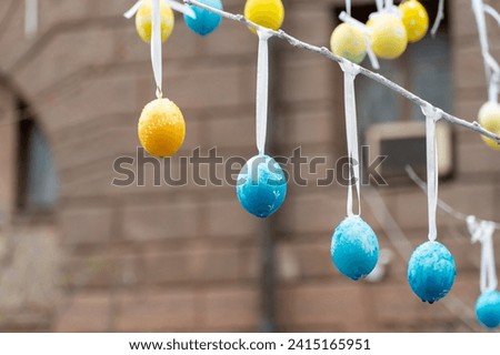 Colorful handmade egges for easter in branches outdoor. Decorating trees with hanging eastereggs in city street. Tradition holiday on christianity religion. Symbol of resurrection to new life.