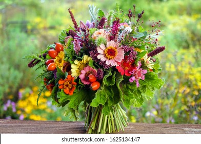Colorful hand-tied bouquet of fresh garden flowers, herbs, scented geraniums, and rose hips