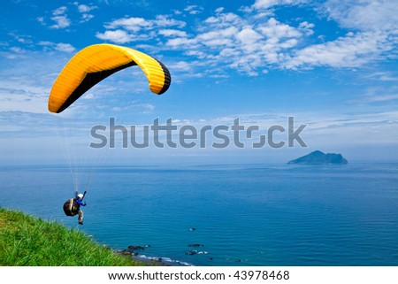 colorful hang glider in sky over blue sea