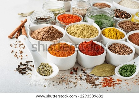 Colorful herbs and spices for cooking dishes. Indian and Asian spices On white stone background closeup