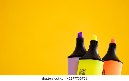 Colorful highlighter pens on yellow background with copy space.