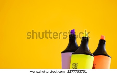 Colorful highlighter pens on yellow background with copy space.